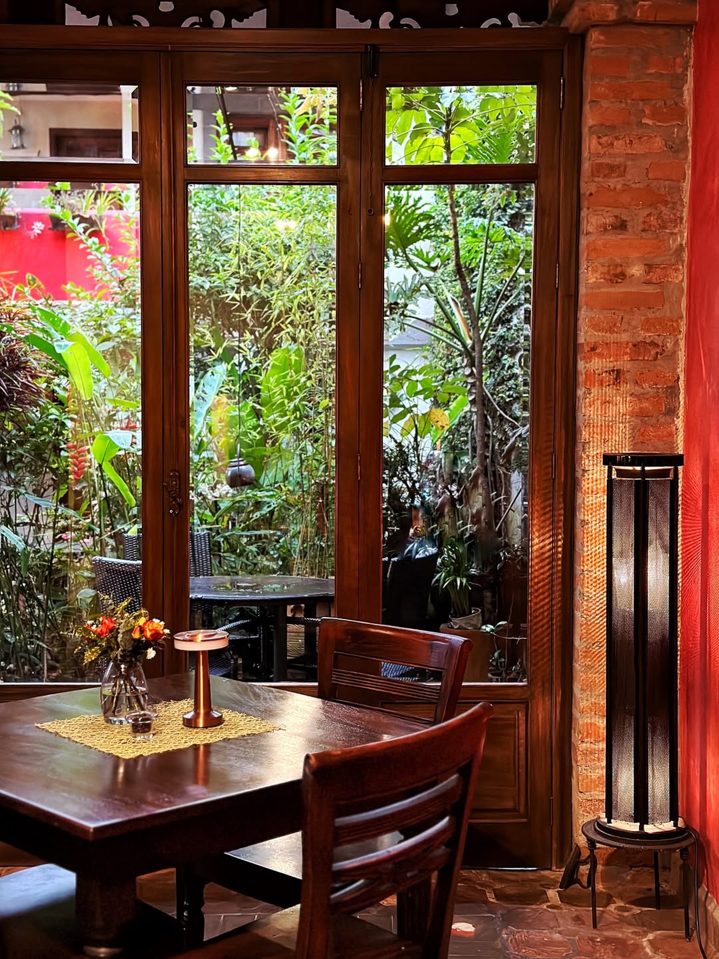 Mesa del comedor junto a puertas de vidrio hacia el jardín